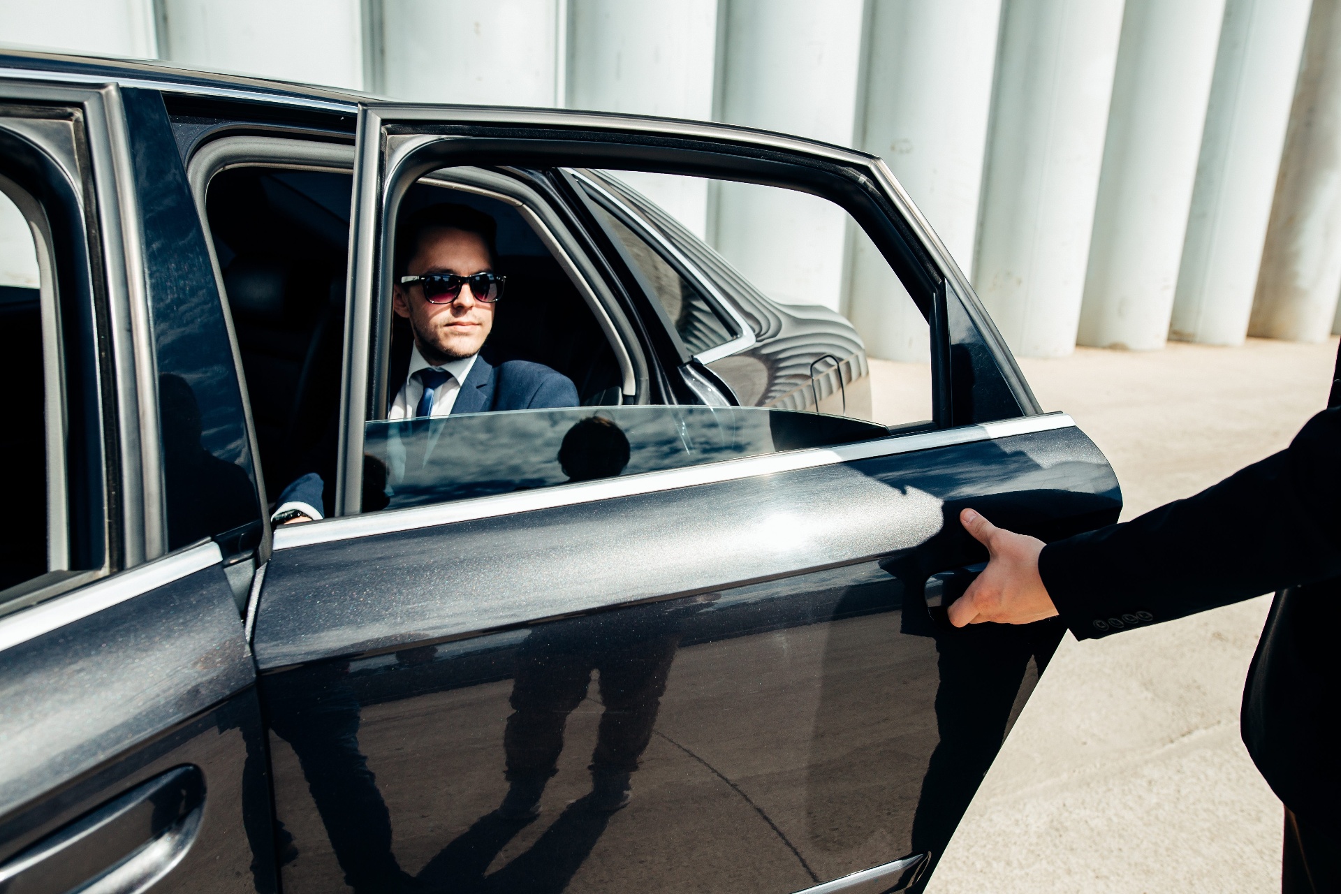 Professioneller Chauffeur öffnet die Wagentür für einen Fahrgast